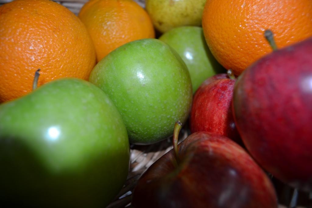 Close-up of fresh oranges and green and red apples in a basket