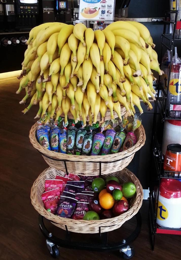 3-tier rolling display stand loaded with bananas, Kettle Creek snacks and fresh fruit
